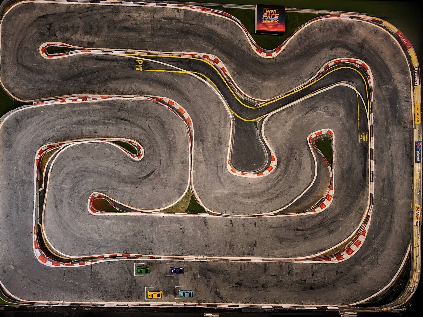 Circuit RC miniature de Cyril, vu de dessus, avec bordures, vibreurs rouge et blanc, stand et piste en asphalte