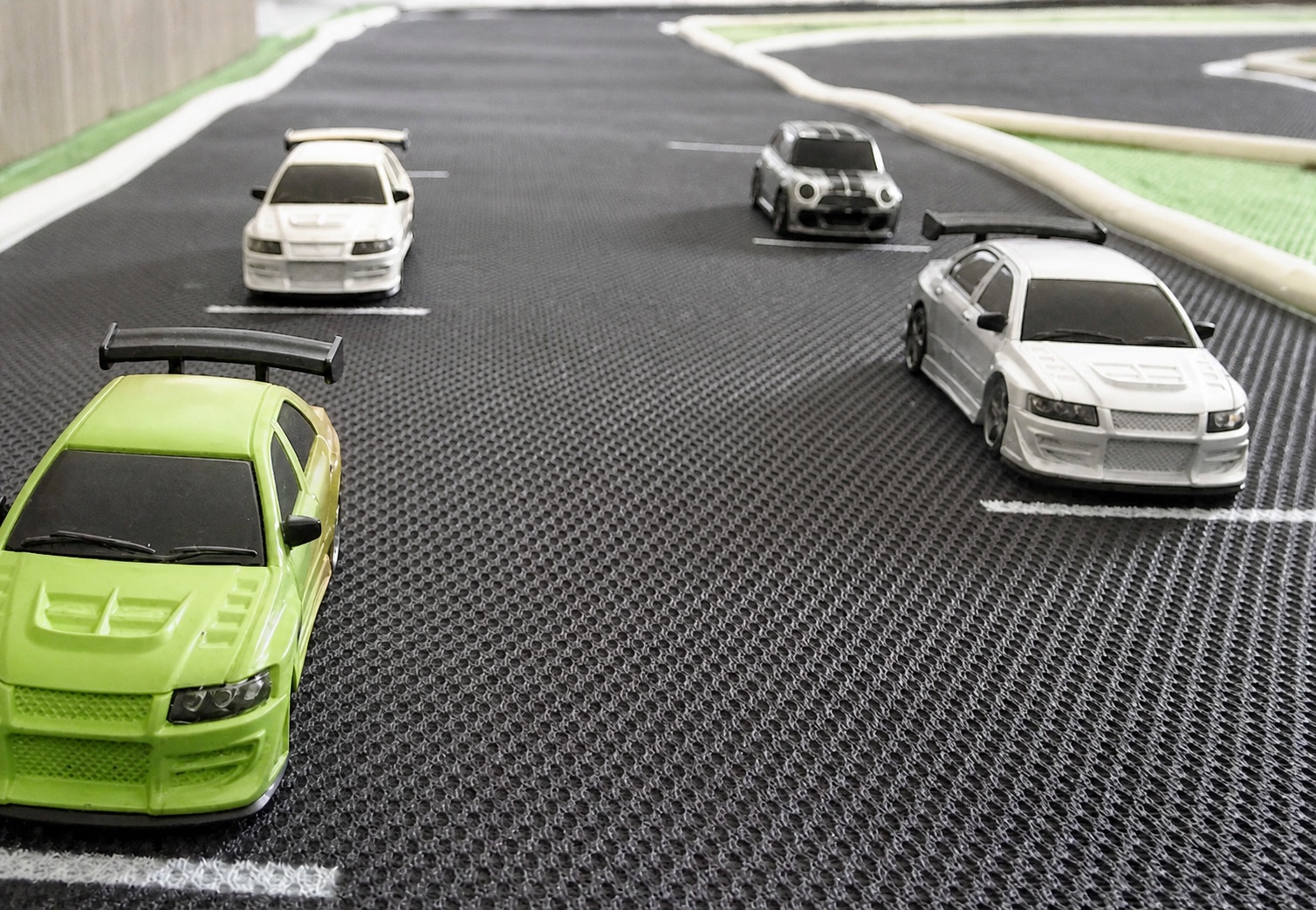 Quatre voitures RC 1/76 alignées sur la grille de départ d’un circuit sur tapis